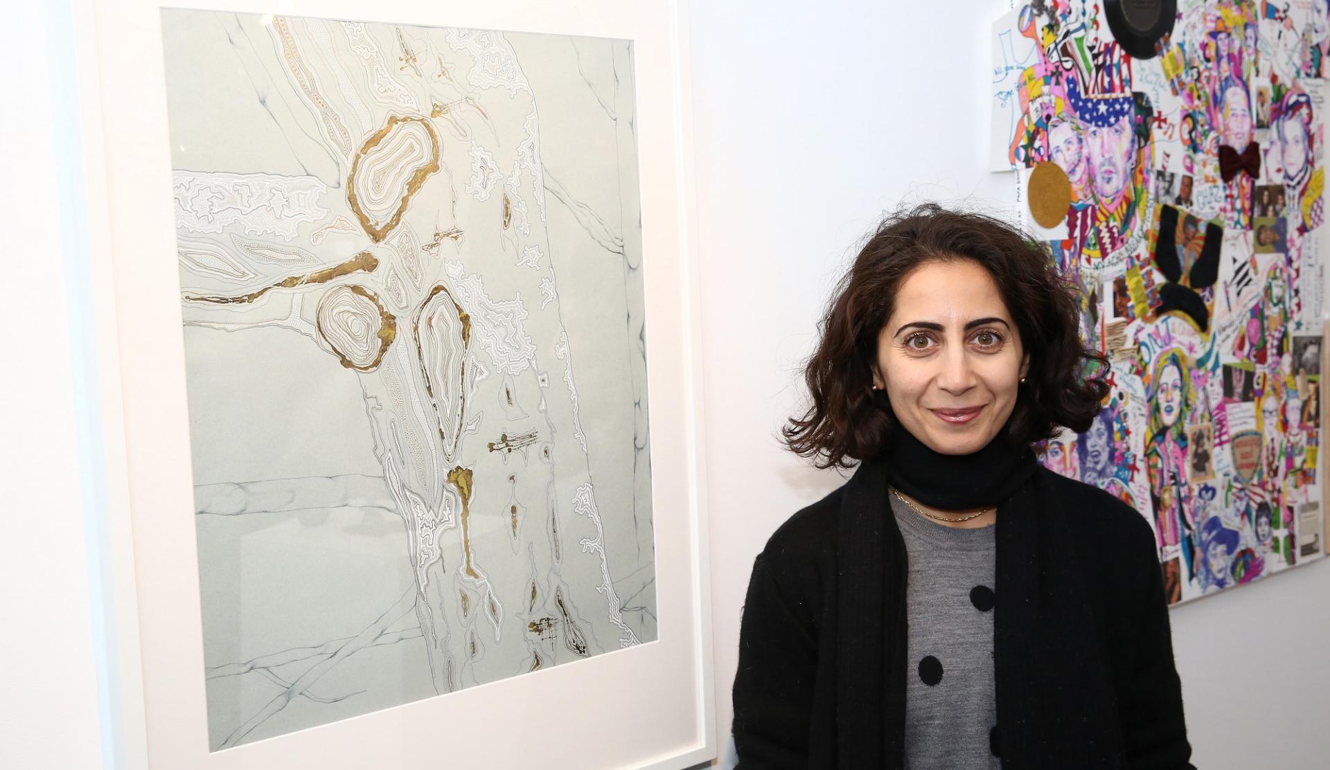 lady standing next to her wining painting hanging in an art gallery