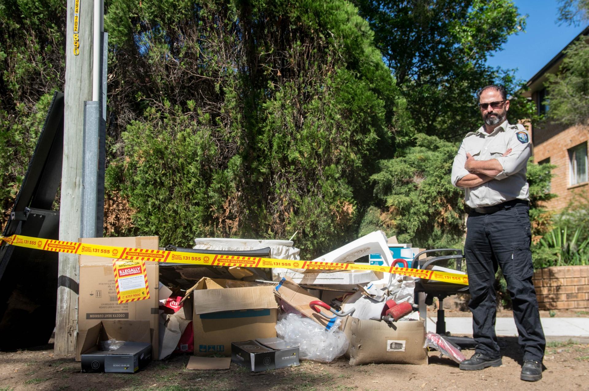 ranger standing next to dumped rubbish