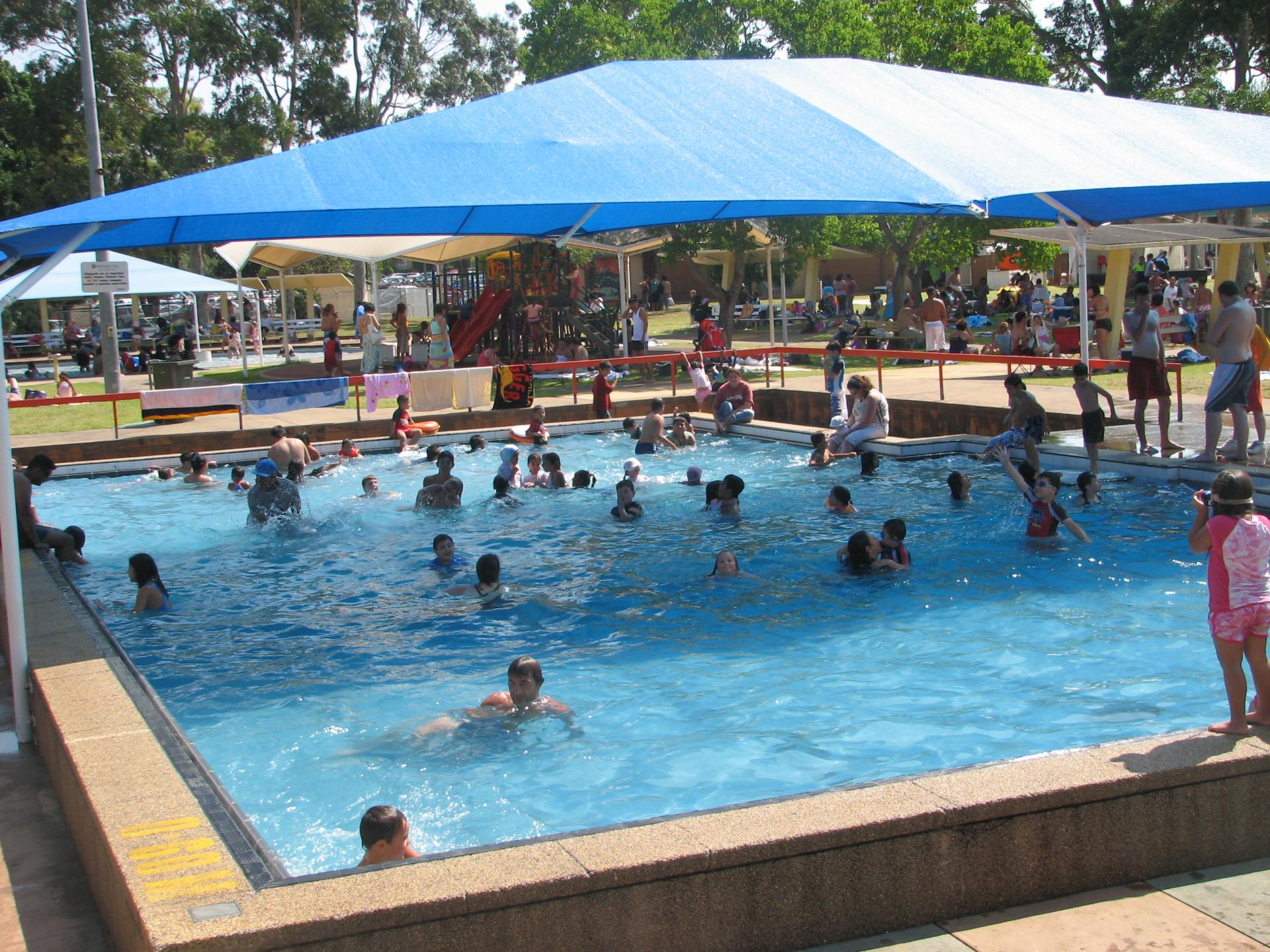 people enjoying pool under a shade cloth