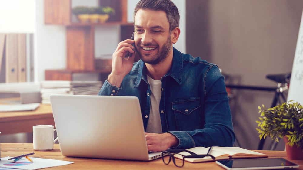 Man talking on phone and on laptop