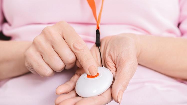 A person holding their personal alarm with one finger on the alarm button