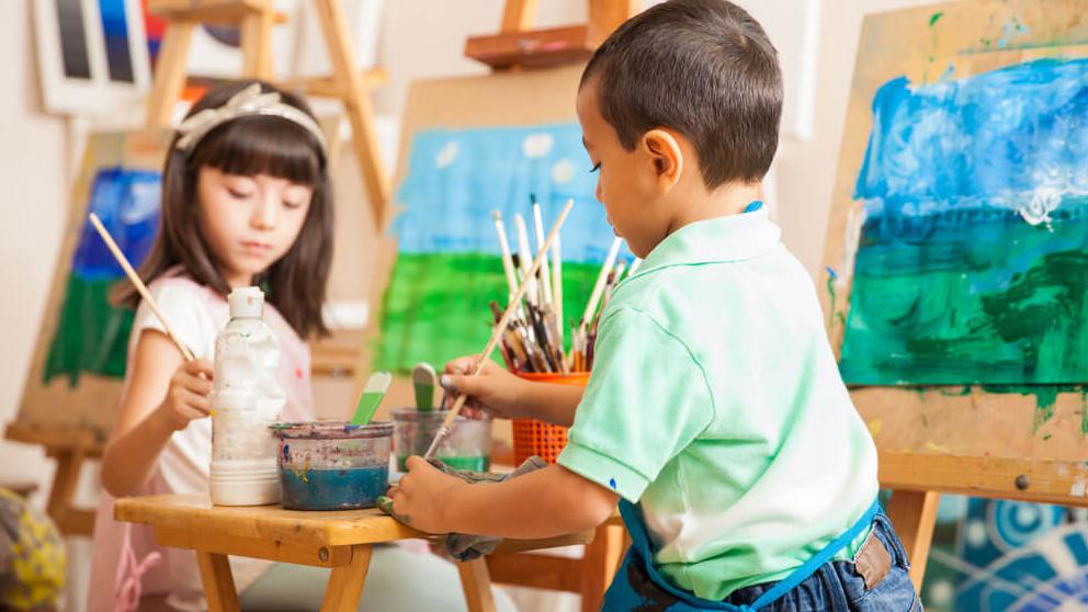 a girl and a boy working on a landscape painting during art class