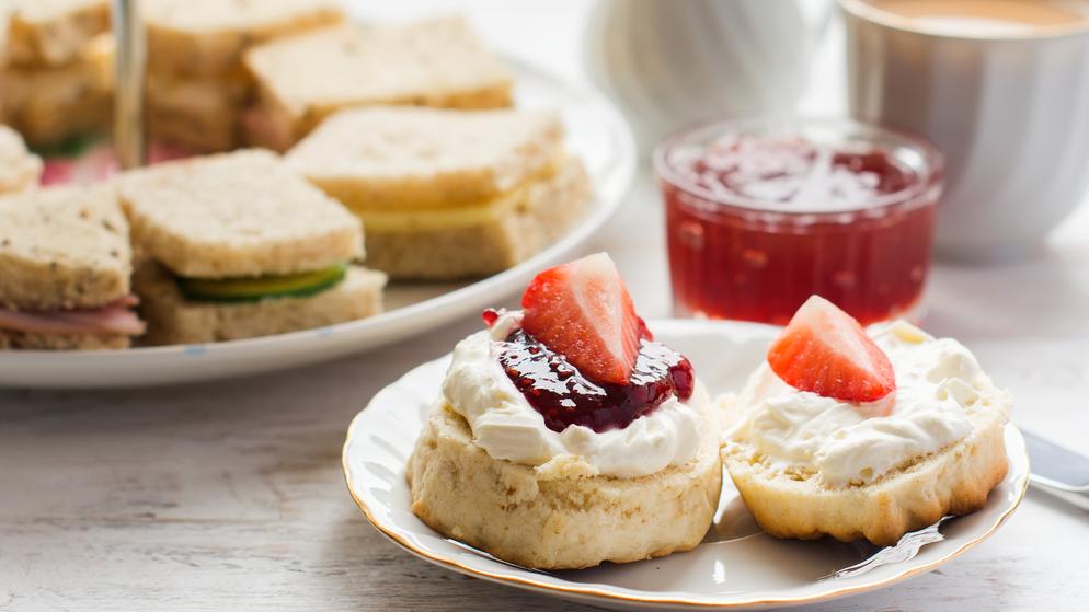 a plate of mixed sandwiches, scones and tea